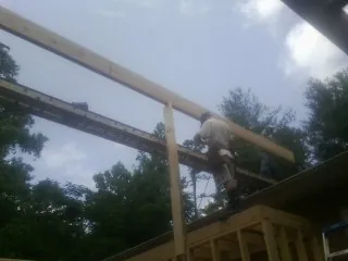 Carpenter setting a ridge beam over a new addition frame — Ice Dam Removal by Roofing Brothers in Hartfield
