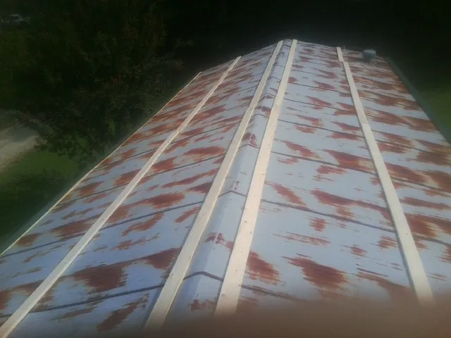 Rusted metal roof panels with new wood purlins before replacement — Storm Damage Roof Repair in Hartfield by Roofing Brothers