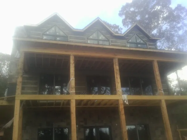 Dormers and porch framing on a large log home under construction — Roof Coating work by our crew in Hartfield