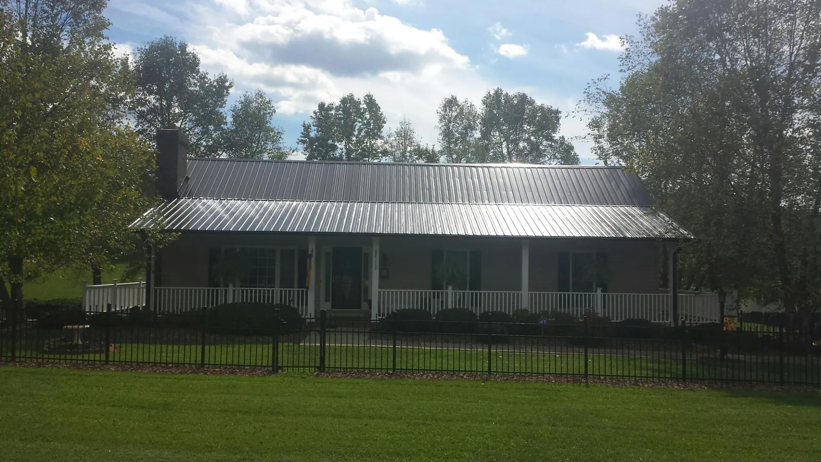 Gray metal roof on a brick ranch with a full width front porch — Gutter Guard Installation work by our crew in Hartfield