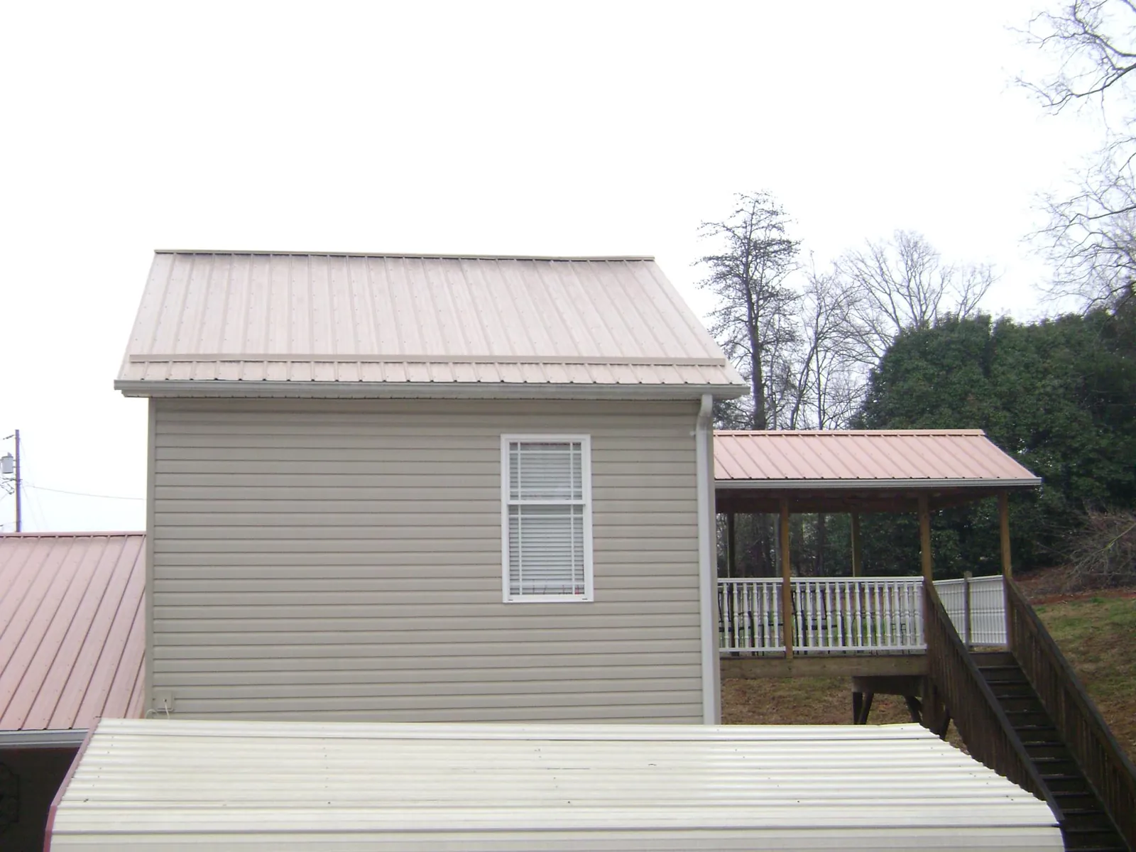 Tan metal roofs on a two story addition and attached porch, from a Roof Replacement job in Hartfield