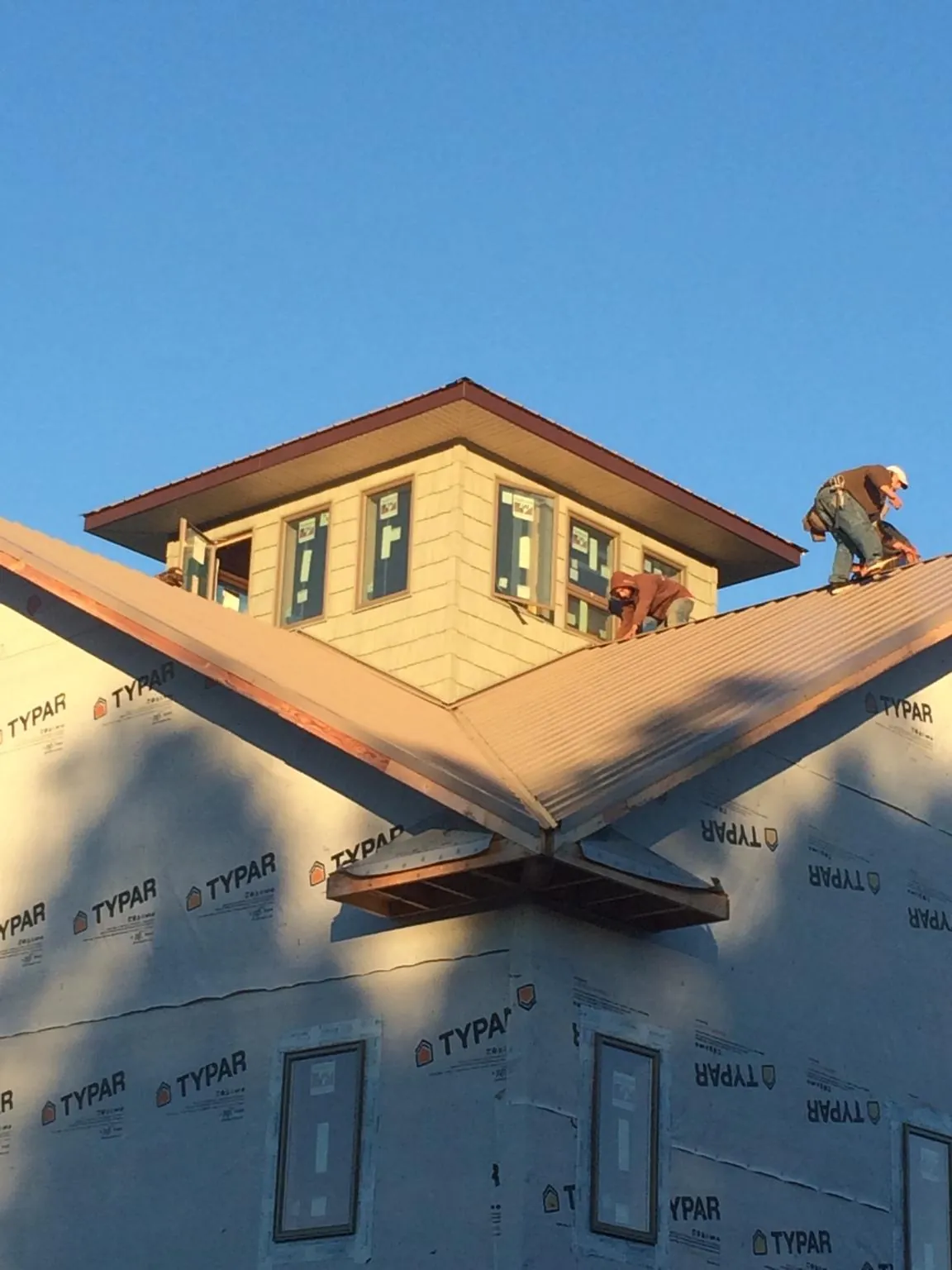 Roofers working around a rooftop cupola on a new metal roof at sunset — Roof Waterproofing in Hartfield by Roofing Brothers